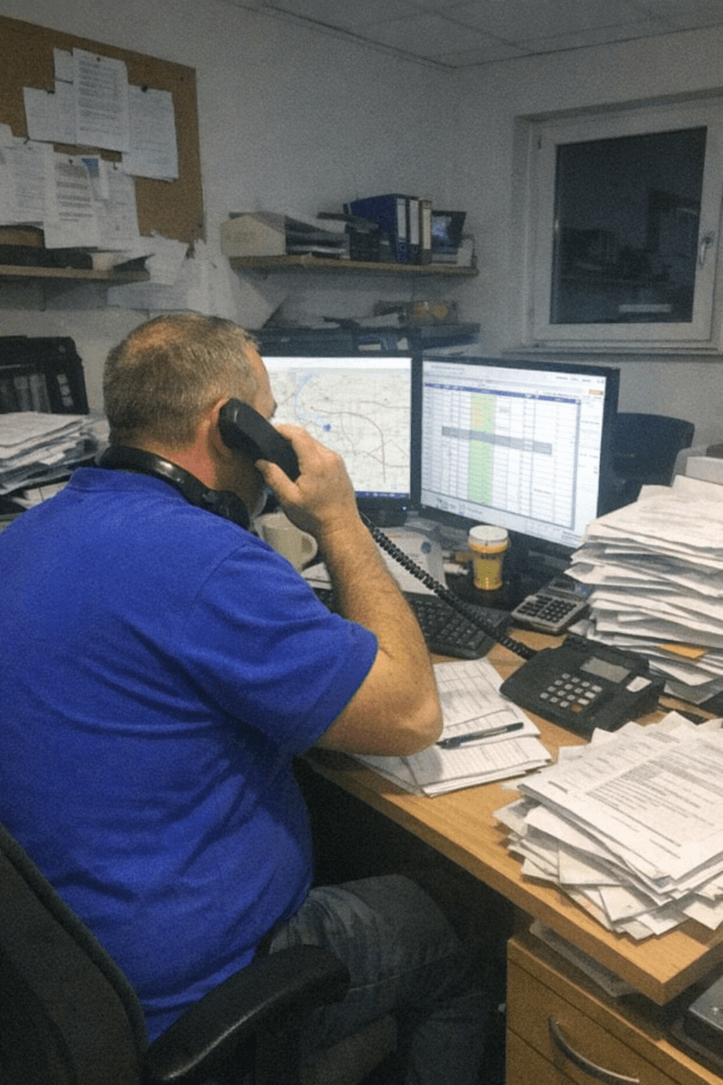 Disponentin sitzt am Schreibtisch, spricht ins Headset und markiert eine Adresse auf einer digitalen Karte